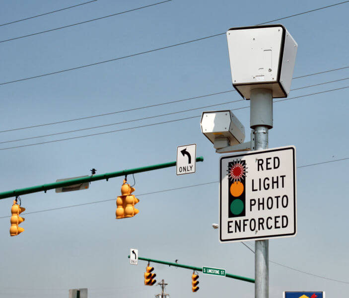 A red light camera on a traffic signal bar