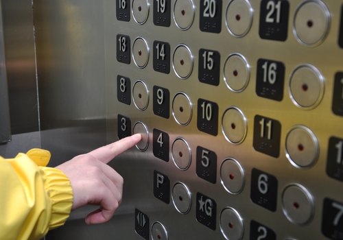 Patron in an elevator image. Elevator with finger pushing floor buttons.