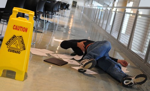 A man who slipped on a wet floor beside a bright yellow caution sign. Landlord Liability For Tenant Injuries in California