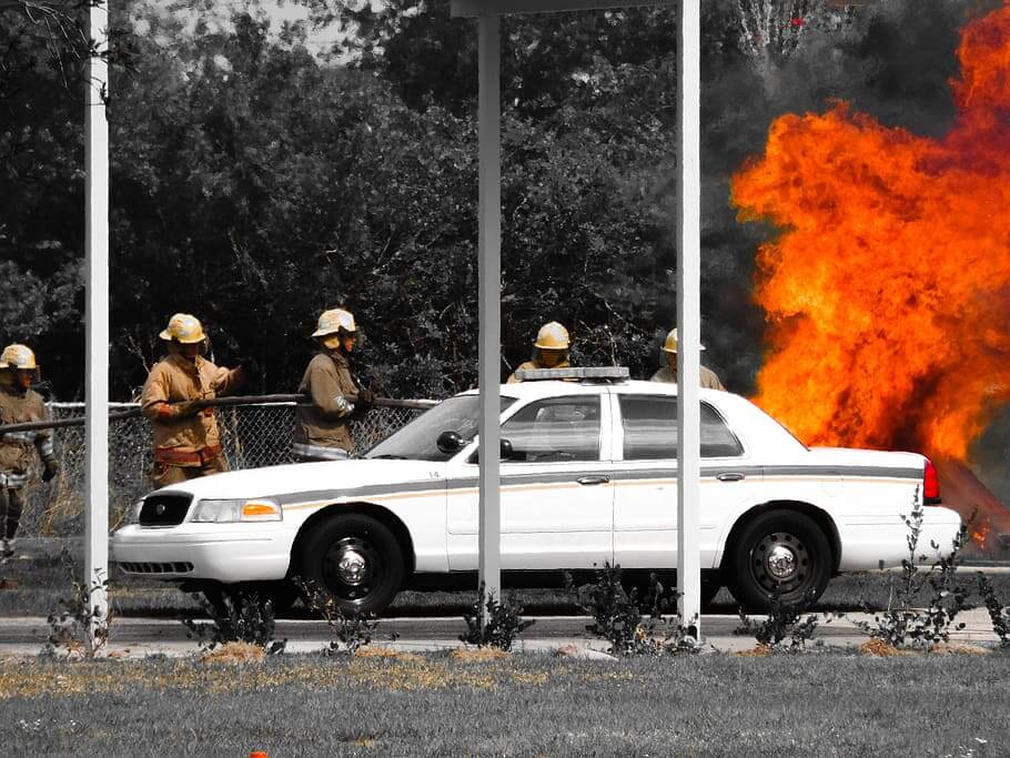 Emergency responders extinguisging flames on a motor vehicle fire burning in flames.