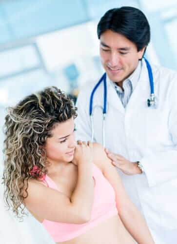 A doctor examining an injured woman's shoulder