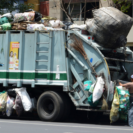 Garbage truck workers cleaning trash from street