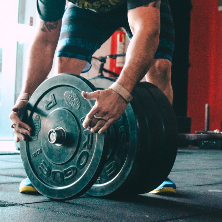 Man stripping plate off barbell at a gym